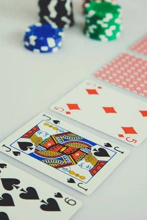 Spelkort utlagda med framsidan upp på ett bord. I bakgrunden syns staplar med casinomarker.